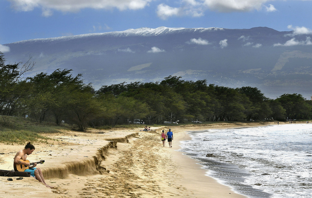 Longview of people walking down beach with mountain in background