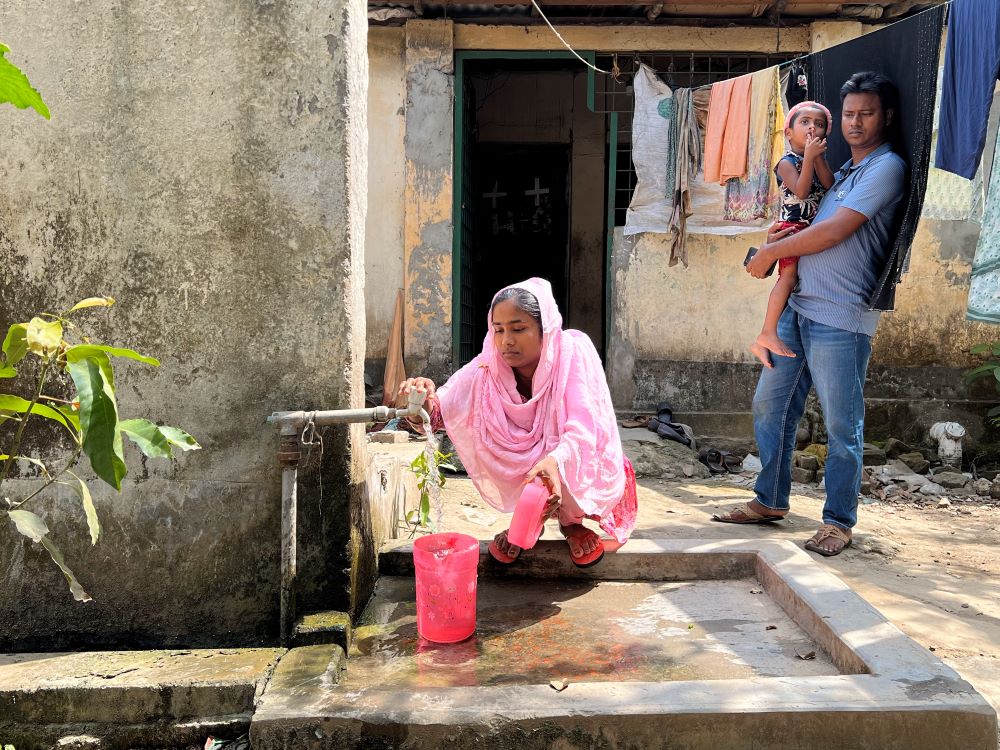 Khadiza Akhter fills up pitchers with water from a spigot in front of her home in Savar, Bangladesh. (Grist/Mahadi Al Hasnat)