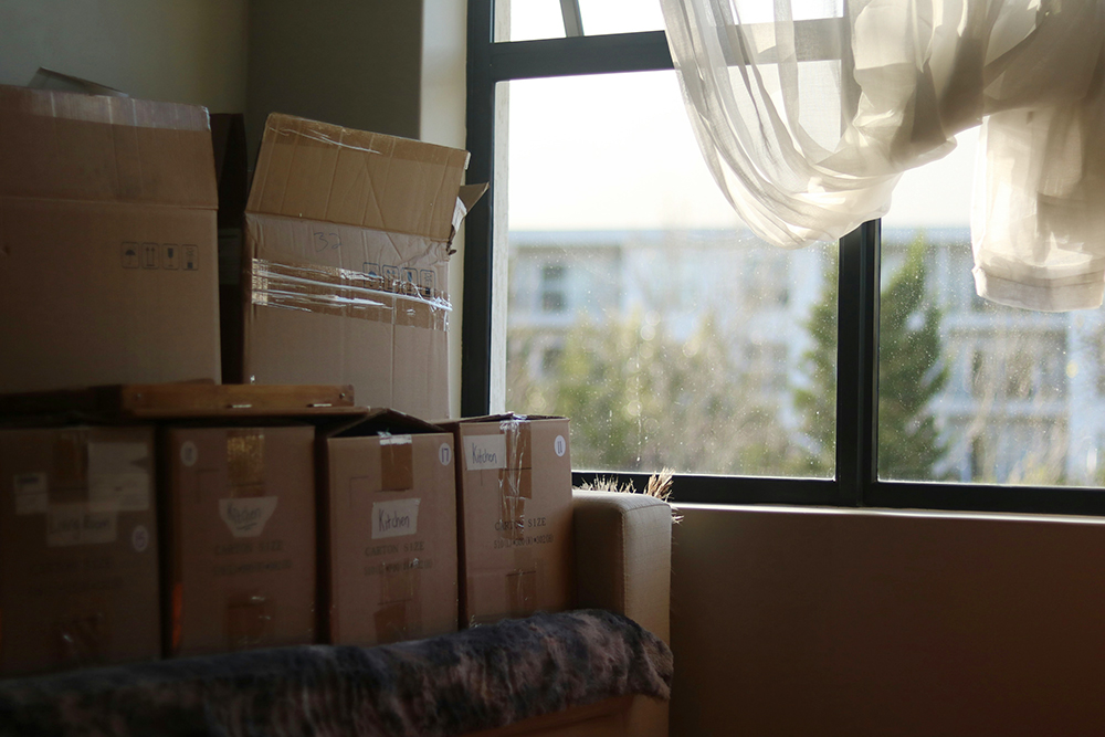 Boxes stacked up next to a window (Unsplash/Alicia Christin Gerald)