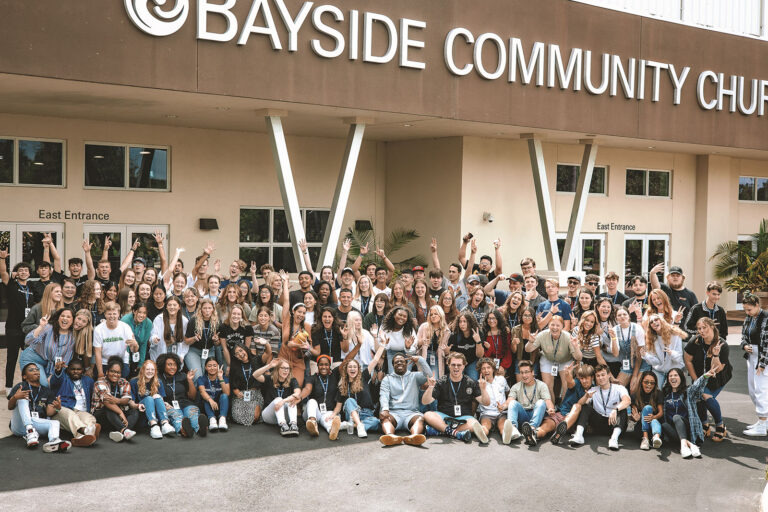 Large group of people stand in front of church building