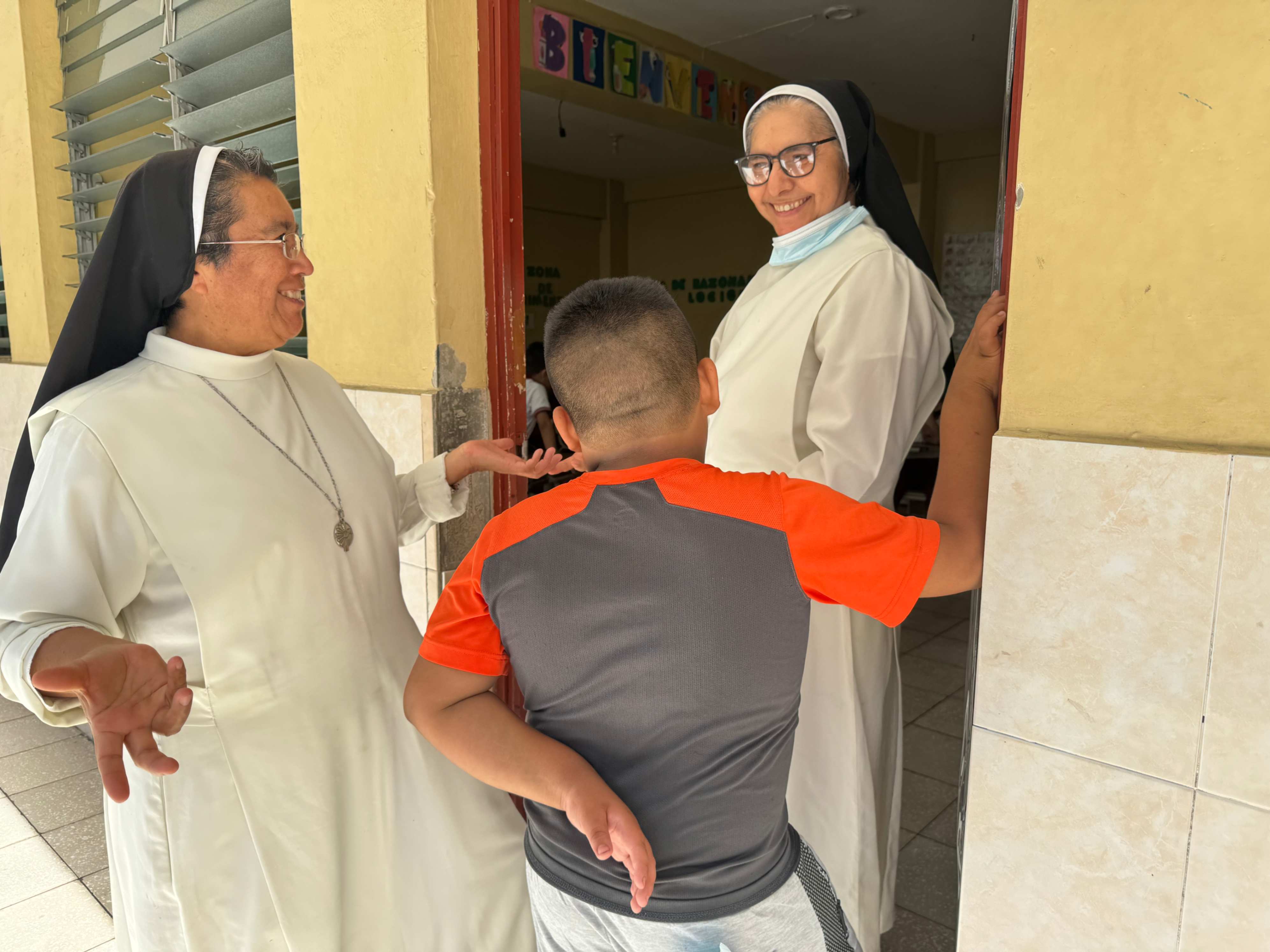 La Hna. Silvia Flores (izquierda) le presenta un nuevo alumno a la Hna. Rosa López Olivar, el 25 de enero de 2024, en el Colegio Eucarístico dirigido por las Hermanas Mercedarias del Santísimo Sacramento en San Salvador, El Salvador. (Foto: GSR/ Rhina Guidos)