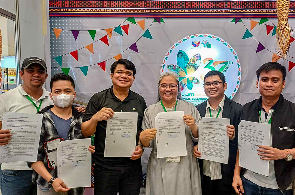 Sr. Ailyn Cayanan, along with agricultural training Institute personnel and the regional director, Pat Andrew Barrientos, sign an approved project proposal for training coconut farmers. (Courtesy of Ailyn Cayanan)