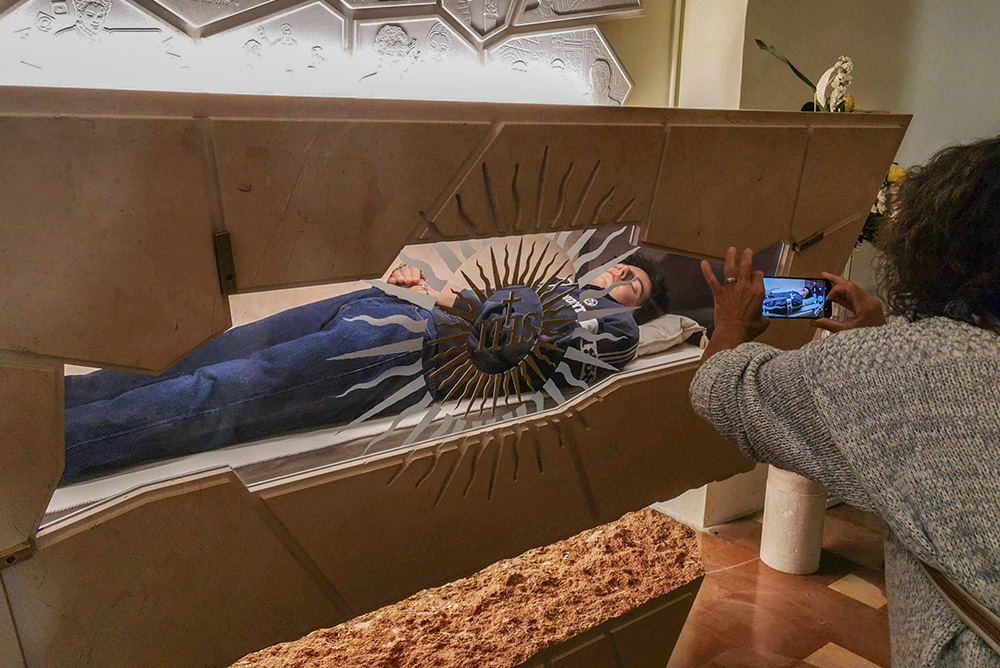 A woman takes a smartphone image of the body of Carlo Acutis in the Church of St. Mary Major in Assisi, Italy, Oct. 9, 2020. (CNS/Junno Arocho Esteves)