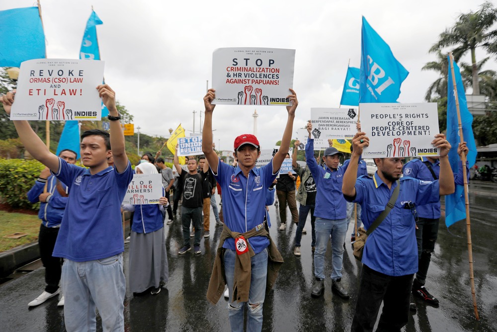 People wearing matching shirt and holding signs march through street. 