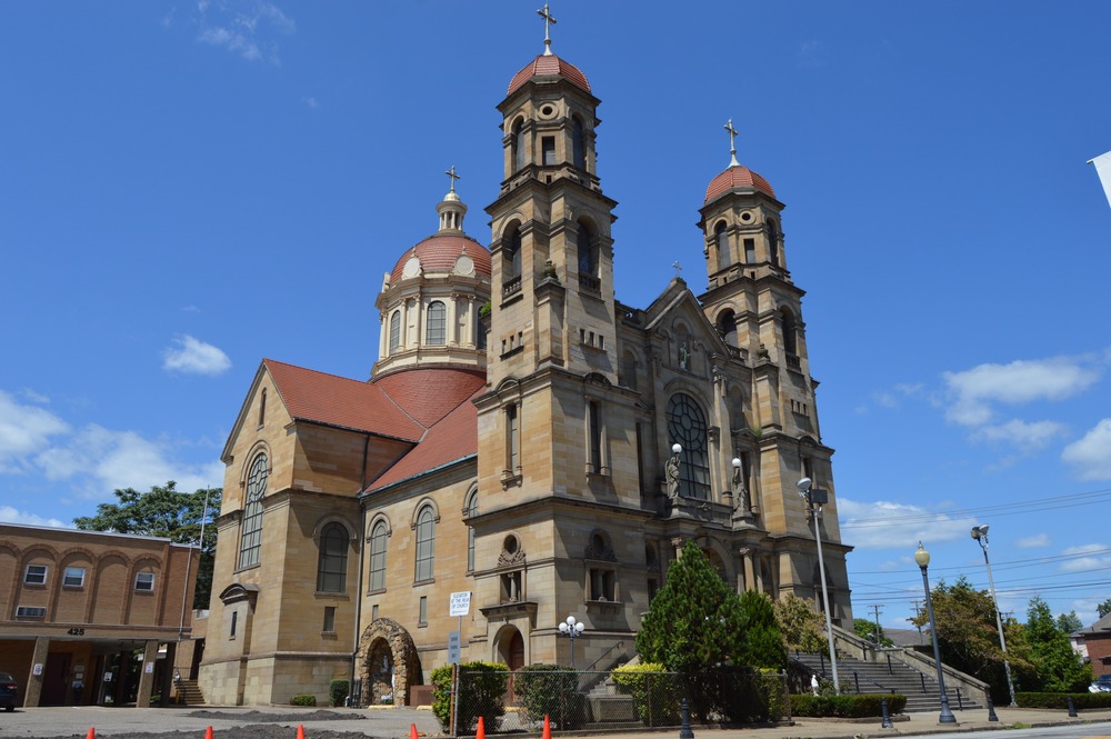 St. Peter Catholic Church, Steubenville, Ohio, Aug. 22, 2024. Large, stone Church building pictured from below, looming against bright blue sky.