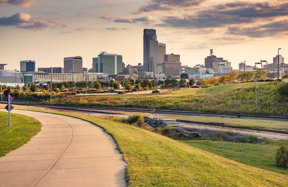 Skyline at dusk shown in distance, long green-lined path foregrounded. 