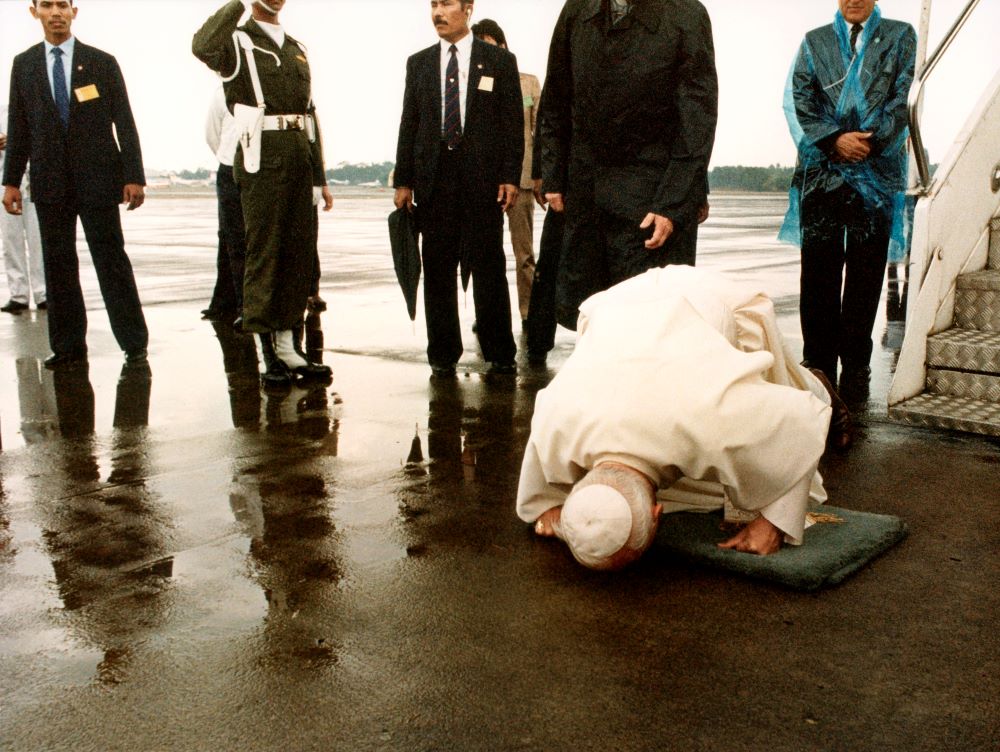 Pope John Paul II kisses a rain-soaked tarmac as he arrives in Jakarta, Indonesia, in 1989. 