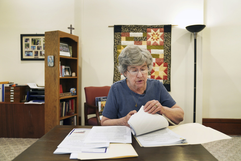 Sr. McCracken sits at desk going through papers. 