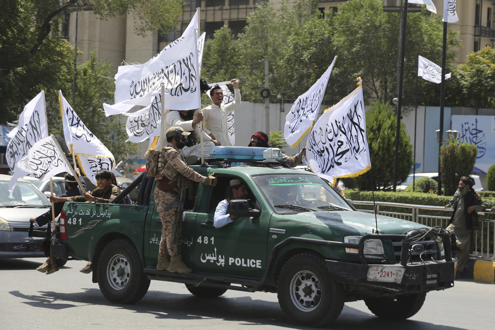 Taliban soldiers, Kabul, Afghanistan, Aug. 14, 2024. Soldiers ride in truck holding flags.