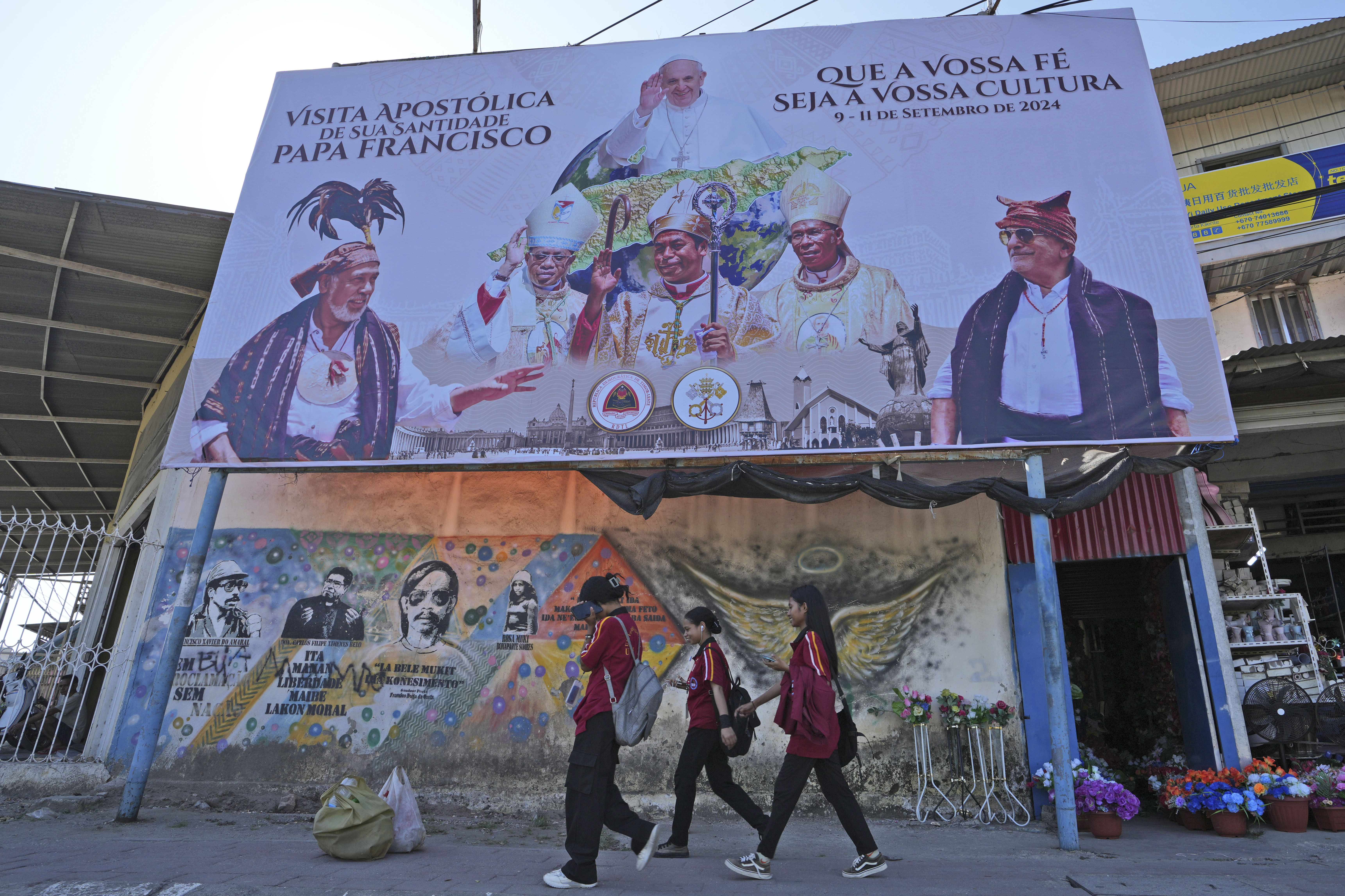 Billboard announcing Pope Francis' trip above mural of national heroes. 