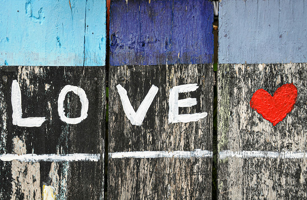 The word LOVE and a red heart painted on a wodden fence (Unsplash/Alex Block)