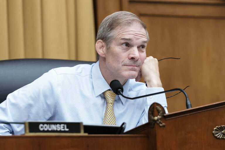 Jordan sits, head on fist, listening. 