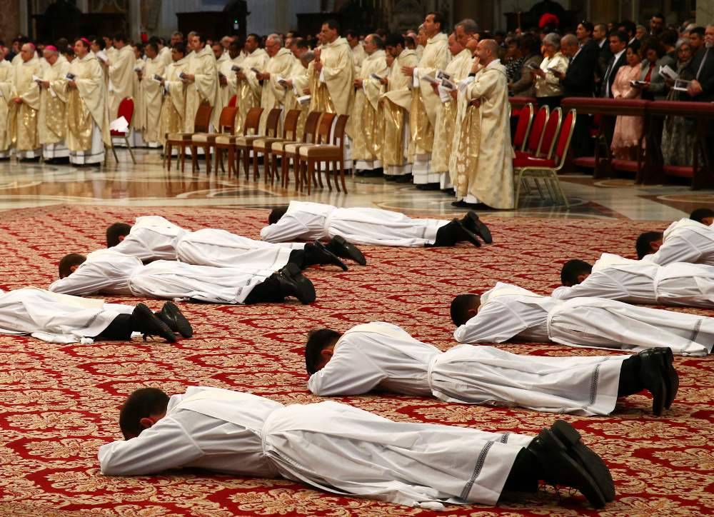 Priests lie prostrate during their ordination by Pope Francis during a Mass in St. Peter's Basilica at the Vatican April 22, 2018. The pope urged the new priests to be merciful with people who approach them, especially in the confessional. (CNS/Reuters/Tony Gentile)