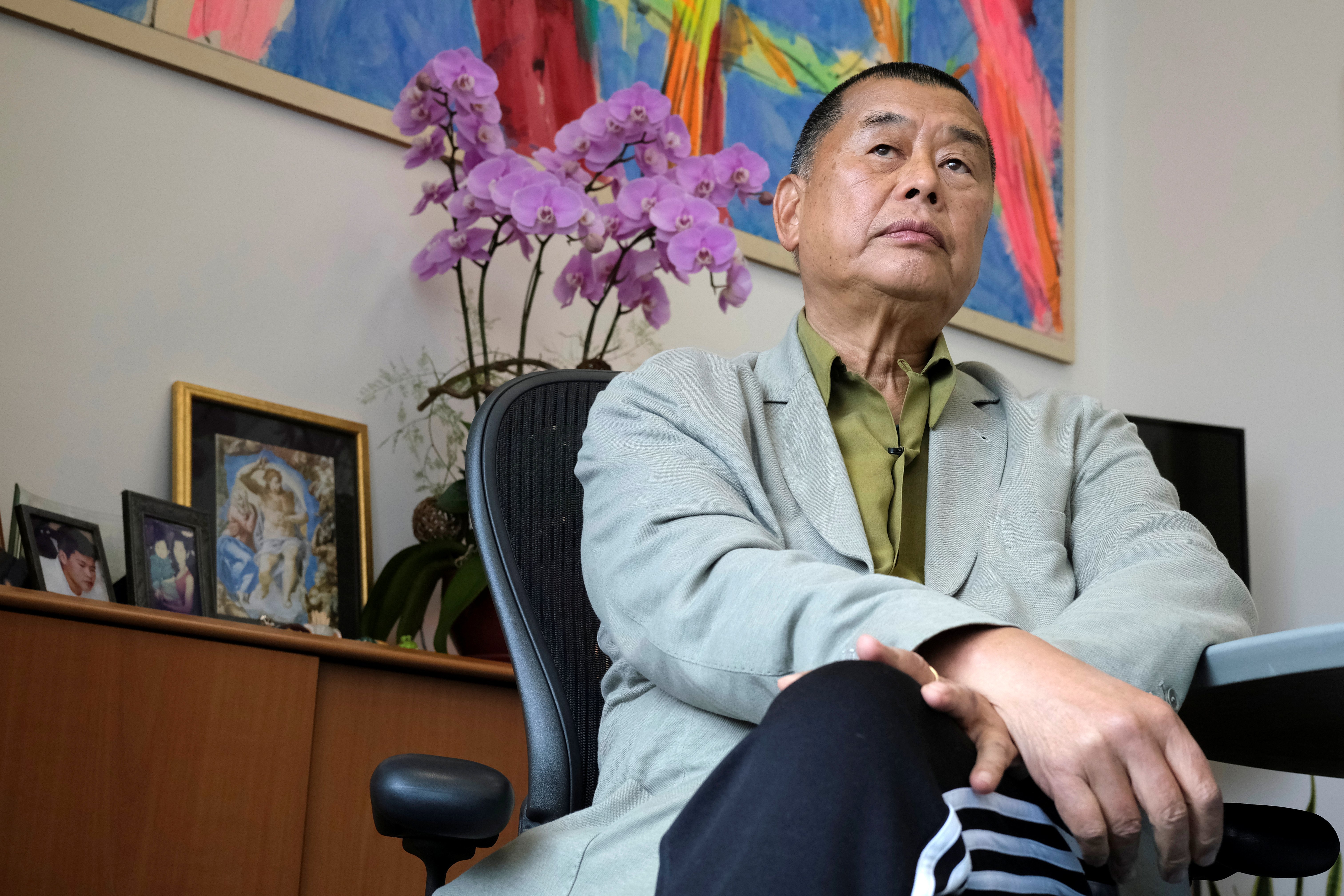 Lai sits at desk looking into camera. 