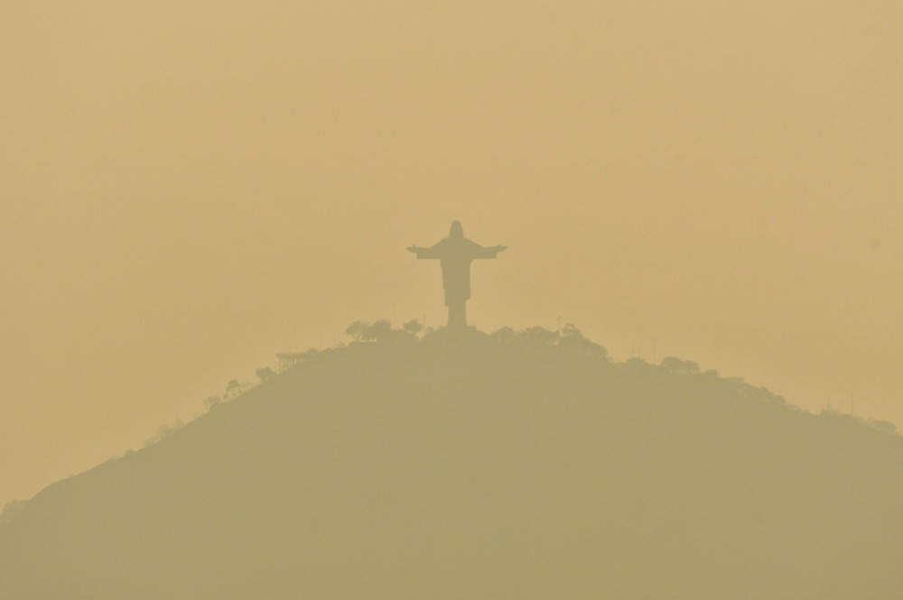 Monumental hilltop statue obscured by sickly, yellow smoke.