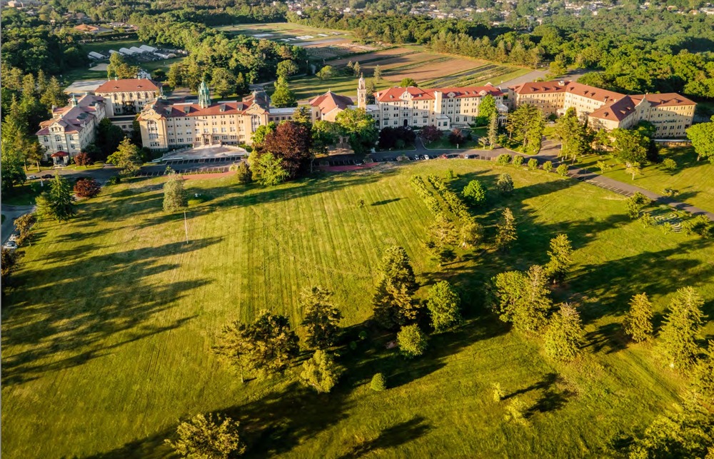 Large complex sitting on sprawling, green lawn seen from above.