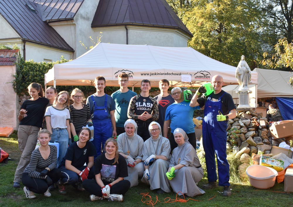 Group assembles for portrait beneath tent pitched in front of church.