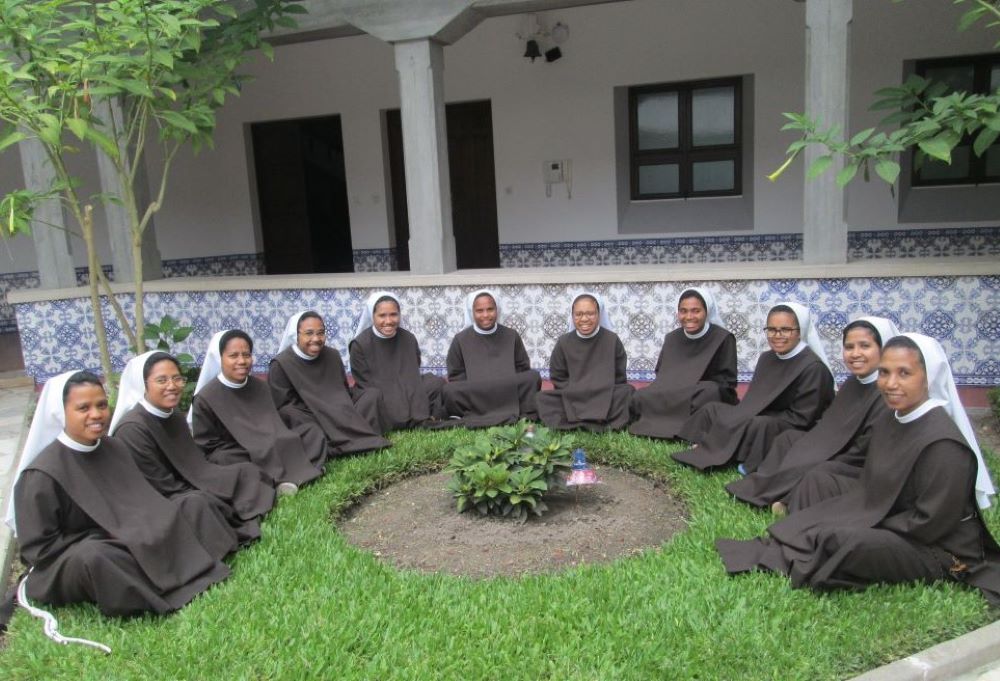 11 Poor Clare sisters sit in semi-circle outside a building.