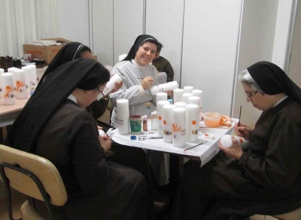 Sisters paint large white candles.