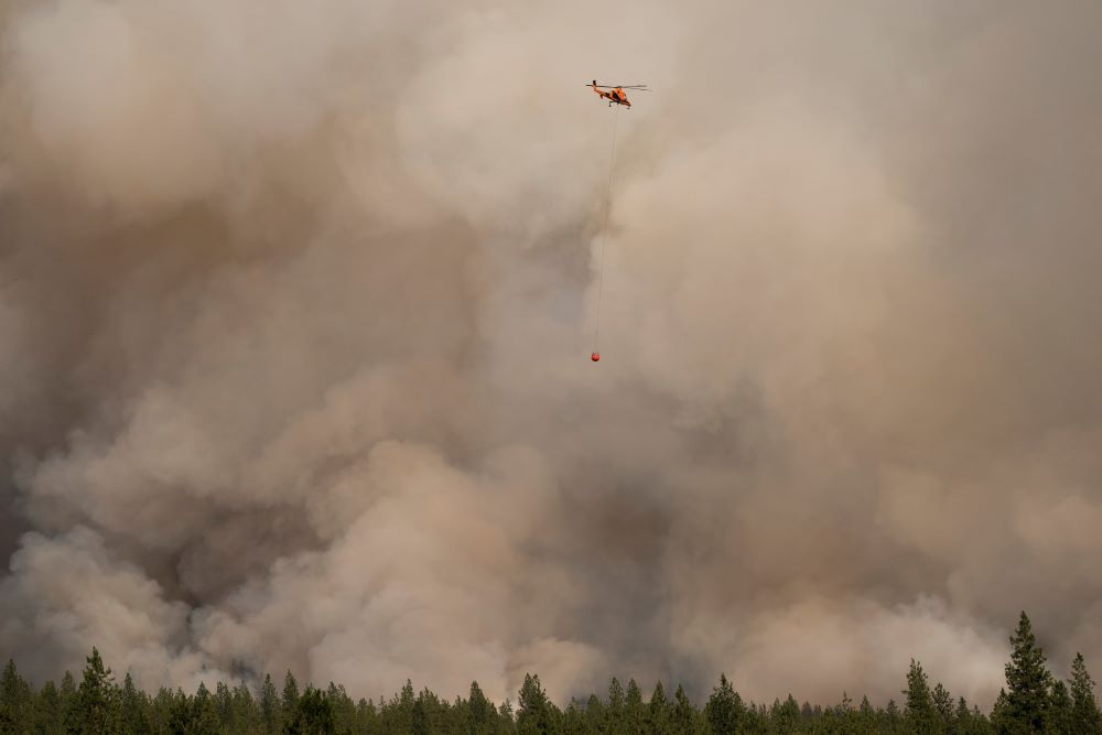 A helicopter in Nespelem, Wash., prepares to drop water on the Chuweah Creek Fire July 14, 2021. 