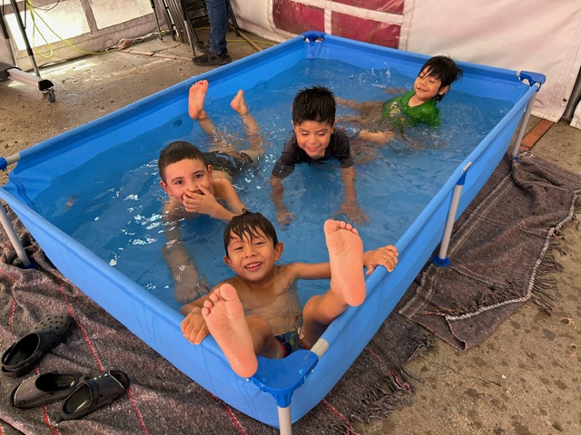 Children cool off in a plastic pool donated by California nonprofit Border Compassion to the Cobina Posada del Migrante shelter in Mexicali, Mexico, where temperatures reached 120 degrees July 8. (Courtesy of Border Compassion)