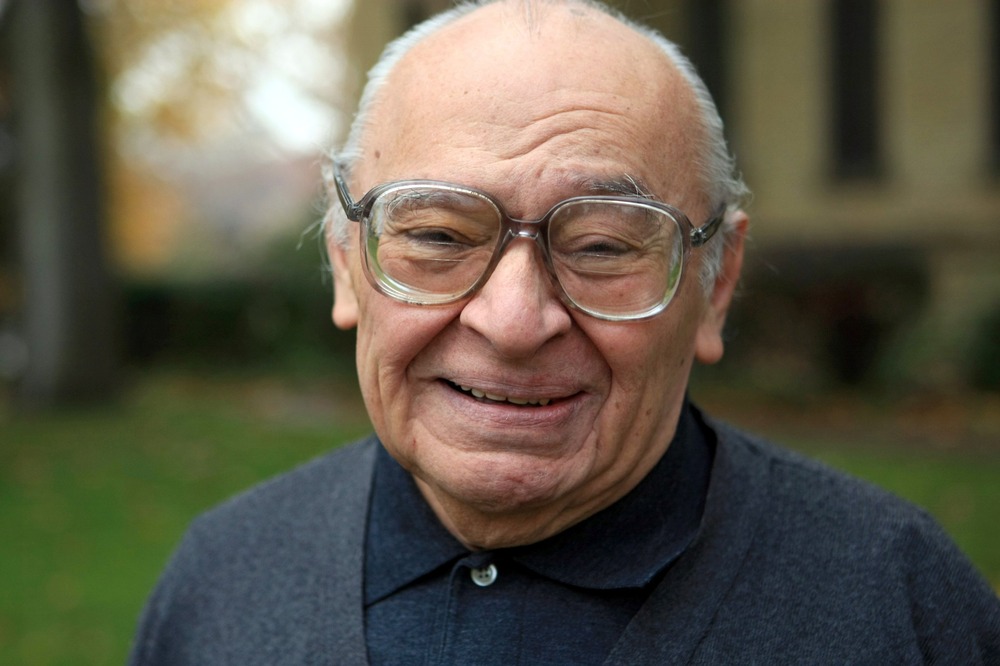 An elderly Gutiérrez faces camera with warm, beaming smile. 