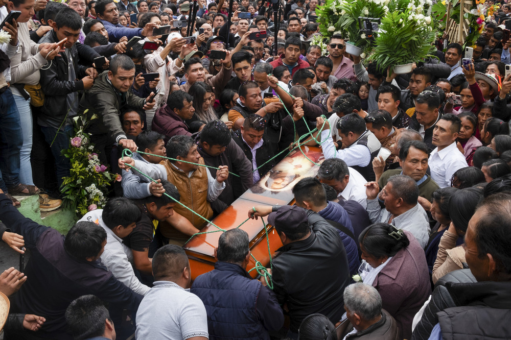 Burial and funeral of murdered Catholic priest and activist Marcelo Pérez, San Andrés Larráinzar, Chiapas state, Mexico, Tuesday, Oct. 22, 2024. Enormous crowd --- dozens deep --- swarms around coffin as it descends.