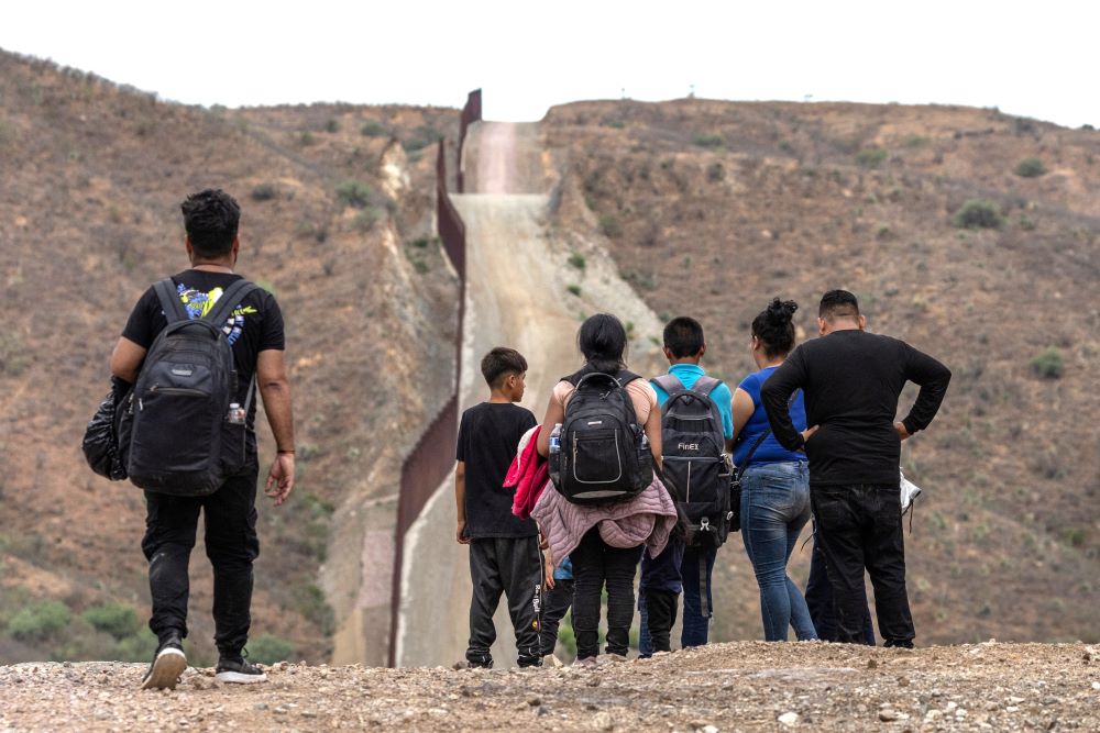 El muro fronterizo se ve en el fondo mientras los migrantes de América del Sur y Central buscan entregarse a los funcionarios de inmigración después de cruzar a los Estados Unidos desde México en Ruby, Arizona, el 24 de junio. (Foto: OSV News/Reuters/Adrees Latif)