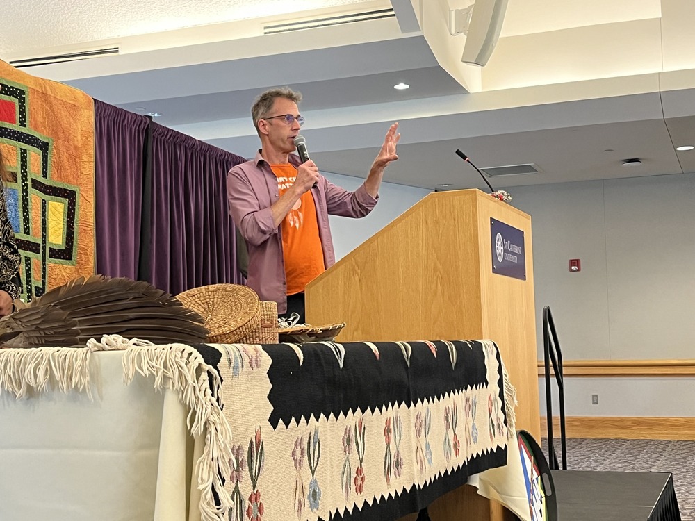 Robert Haarman, director of the Office of Indian Ministry of the Archdiocese of St. Paul and Minneapolis and community minister at Gichitwaa Kateri Catholic Church in Minneapolis, Oct. 4, 2024. Haarman stands at a podium, holding mic.