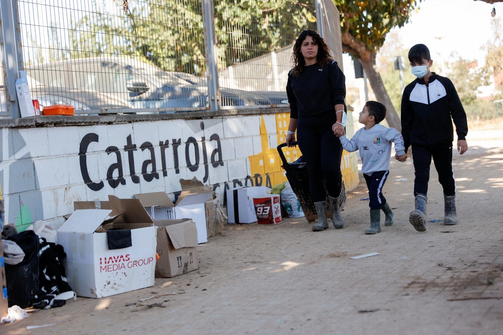 Valencia flood aftermath, Nov. 11, 2024. Woman walks with two sons.
