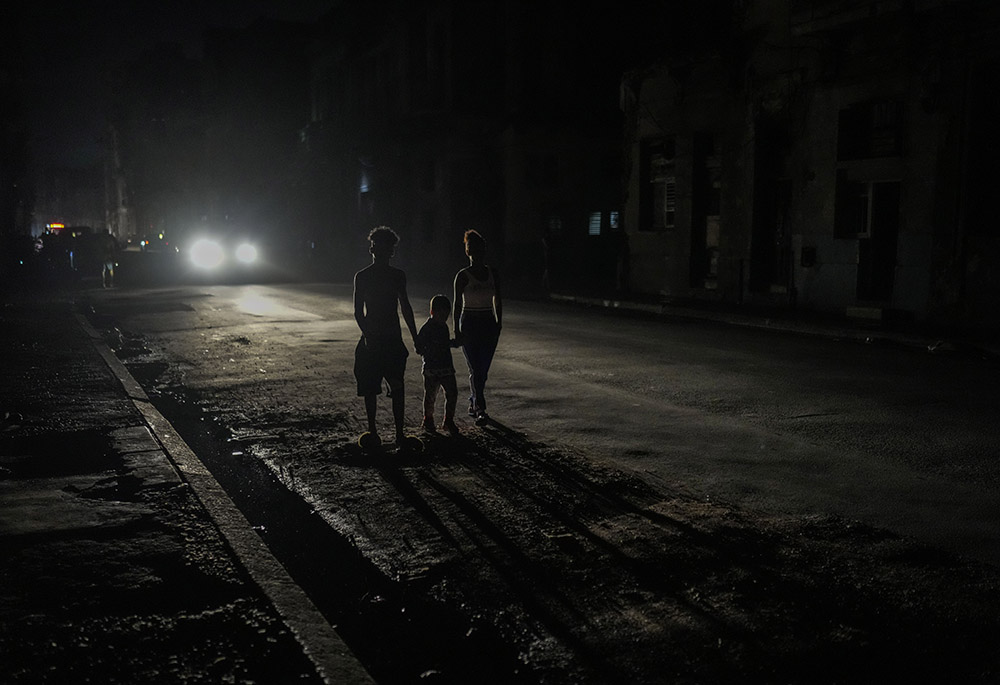 Los faros de un automóvil iluminan a los residentes durante un apagón luego de que una importante planta eléctrica falló el 18 de octubre en La Habana, Cuba. (Foto: AP/Ramon Espinosa, archivo)