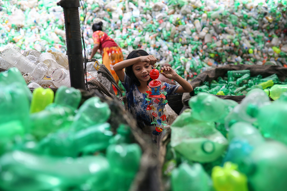 A girl plays with a toy found in a plastic recycling factory in Dhaka, Bangladesh, July 8, 2019. (CNS/Reuters/Mohammad Ponir Hossain)