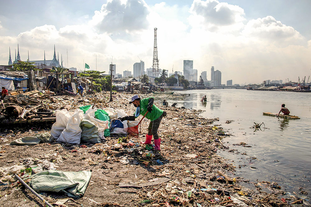 A member of River Warriors rakes through trash on the banks of the heavily polluted Pasig River in Manila, Philippines, June 18, 2021. The River Warriors is a group of volunteers founded more than a decade ago with the sole purpose to pick up garbage in and around the river. (CNS/Reuters/Eloisa Lopez)