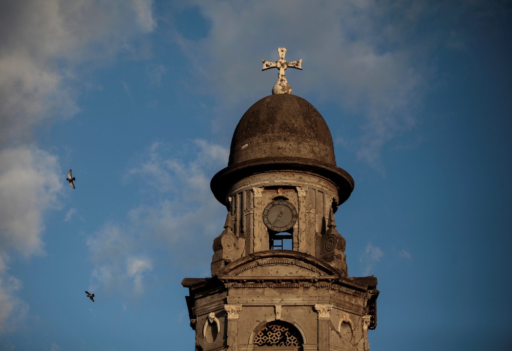 Close-up of stone tower against blue and white sky.