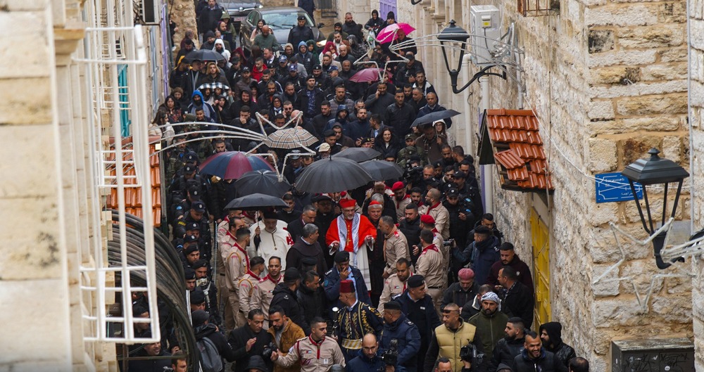 Vatican officials, Bethlehem, Dec. 24, 2023. Narrow, antiquated street depicted aerially, and filled with clergy and faithful.