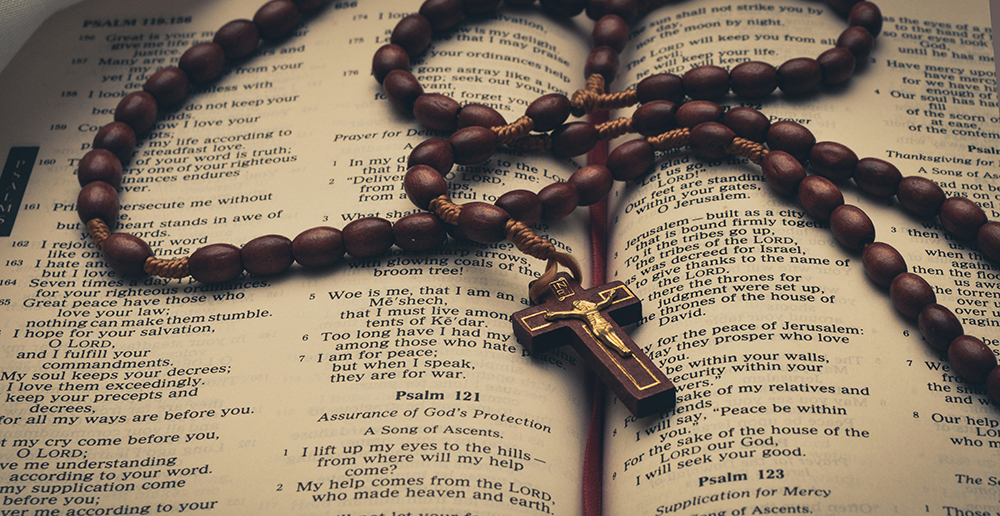 A rosary laid out across an open Bible (Unsplash/Anuja Tilj)