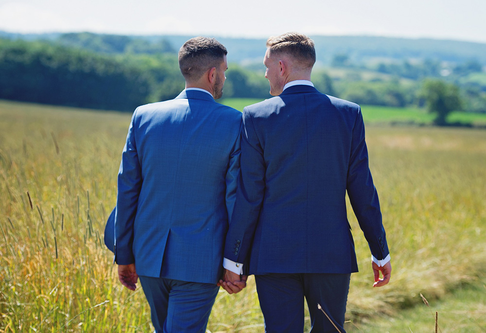 Photo illustration shows two suited men walking outside holding hands. (Pixabay/LollipopPhotographyUK)