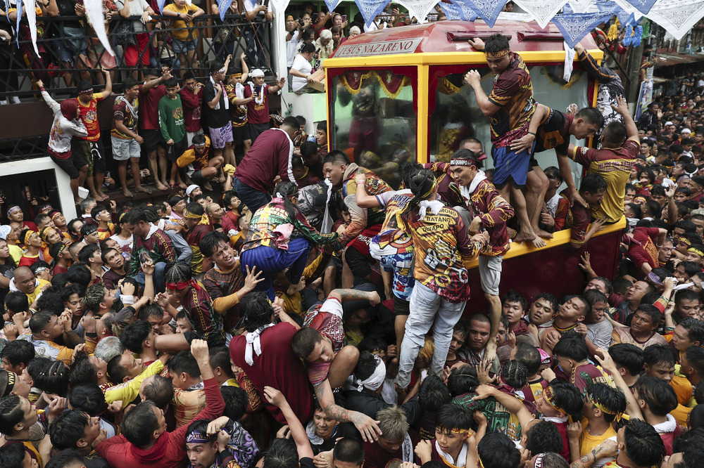 Annual procession of Jesus Nazareno, Manila, Philippines, Jan. 9, 2025. Large glass carriage contains life-size statue; it is surrounded my mammoth crowd who cling and pull to the carriage.