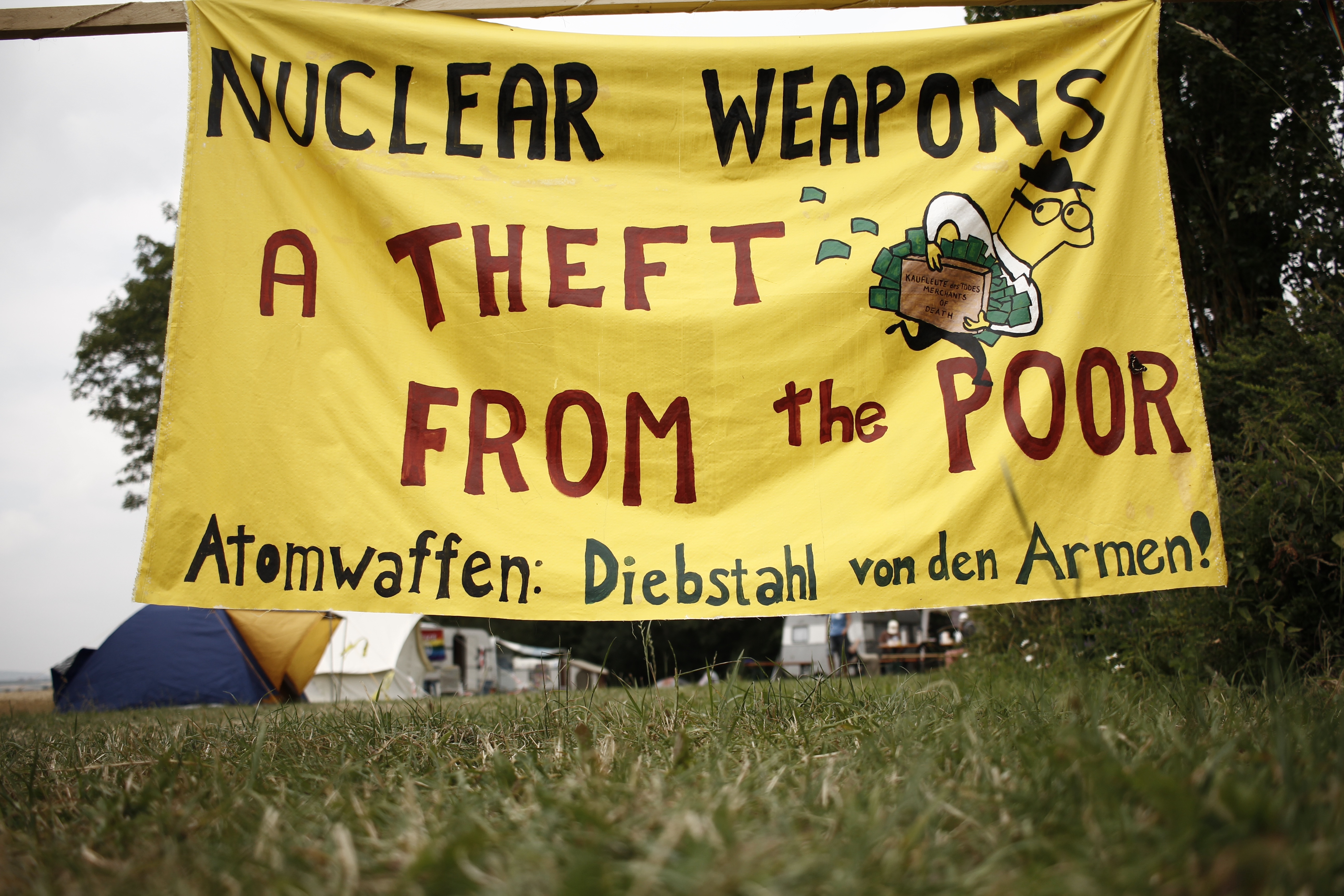 SusanCrane2.jpg A yellow painted banner from Crane’s protest reads "NUCLEAR WEAPONS: A THEFT FROM THE POOR" in red text.