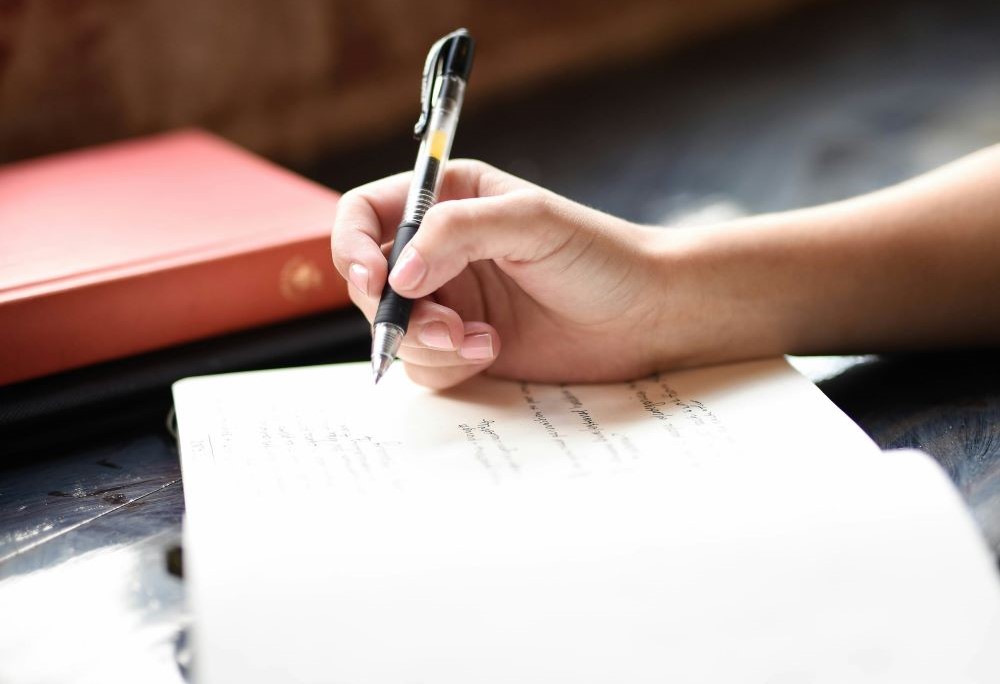 hand with pen, writing in book