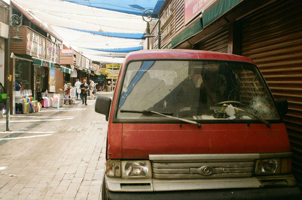 A red van with a cracked windshield parked on the side of the street.