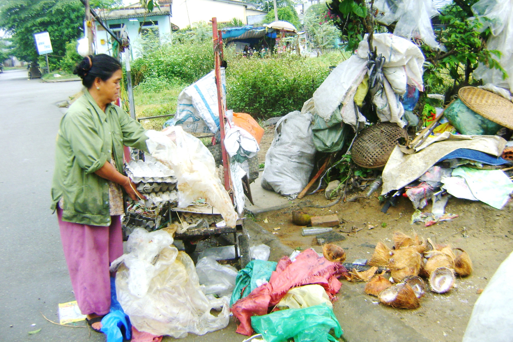 Nguyen Thi Voi loads her three-wheeled cart with scraps on Mar. 5 in Phong Dien district of Thua Thien Hue province. (Joachim Pham)