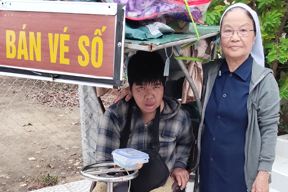 Sr. Anna Le Thi Hue gives food to a disabled woman who is forced to sell lottery tickets by her relative on Mar. 6 in Phu Loc district of Thua Thien Hue province. (Joachim Pham)