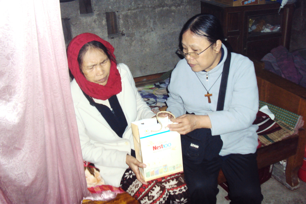 Sr. Mary Vu Thi Ngoc (right) offers a gift to a patient who suffers from domestic abuse on Mar. 6 in Phong Dien district of Thua Thien Hue province, Vietnam. (Joachim Pham)
