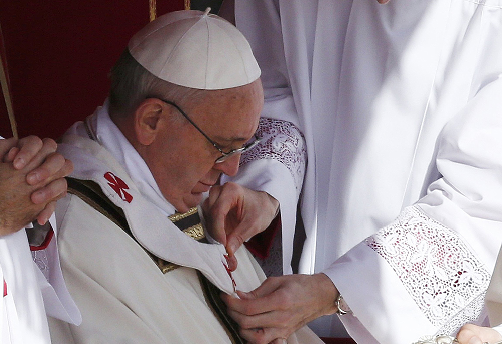 The pallium is fitted on Pope Francis during his inaugural Mass in St. Peter's Square at the Vatican March 19, 2013. With his fisherman's ring and the pallium, the main symbols of the Petrine office, the pontiff chose styles in continuity with two of his predecessors. (CNS/Reuters/Stefano Rellandini)
