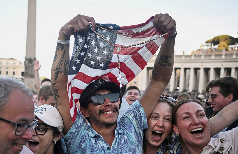 A man holding a rosary and U.S. flag reacts as Cardinal Robert Francis Prevost, who has chosen the papal name Leo XIV, appears on the central balcony of St. Peter's Basilica at the Vatican May 8, 2025, following his election during the conclave. (OSV News/Reuters/Dylan Martinez)