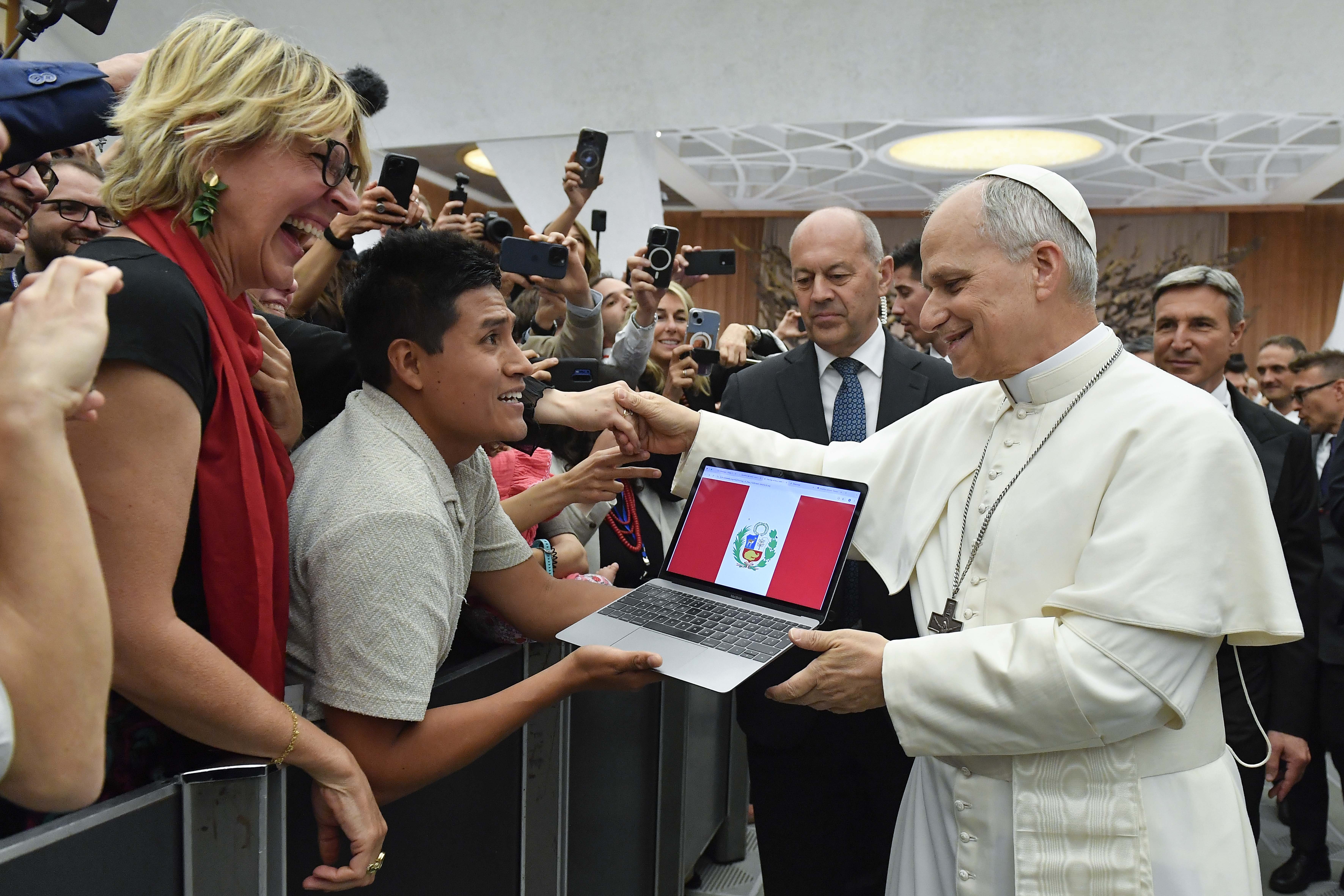 Pope Leo XIV greets a man with a laptop depicting the flag of Peru during a meeting at the Paul VI Audience Hall at the Vatican May 12, 2025. Leo met with representatives of the media who covered his election. (OSV News/Vatican Media)