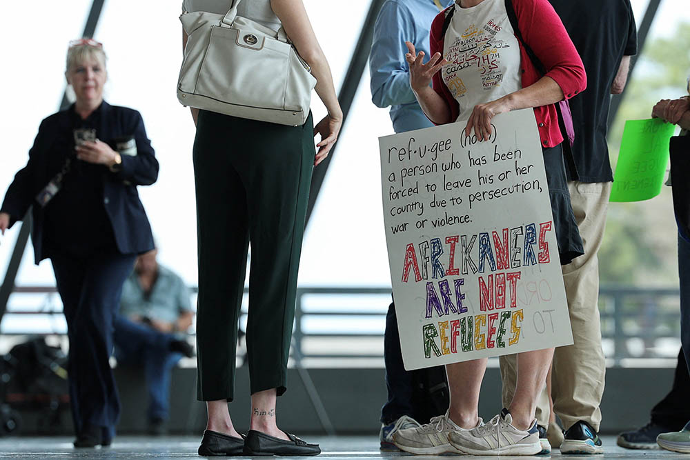 A person holds a sign on the day people from the first group of white South Africans granted refugee status for being deemed victims of racial discrimination under U.S. President Trump's Refugee plan, arrived at Dulles International Airport in Virginia May 12, 2025. (OSV News/Reuters/Kevin Lamarque)