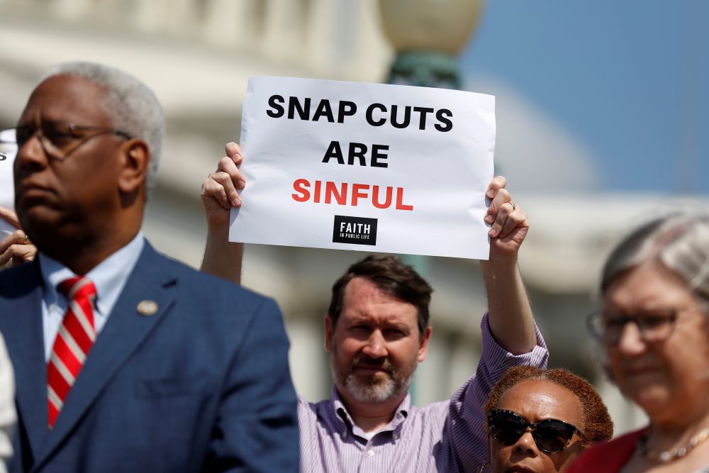Man holds sign: SNAP cuts are sinful.