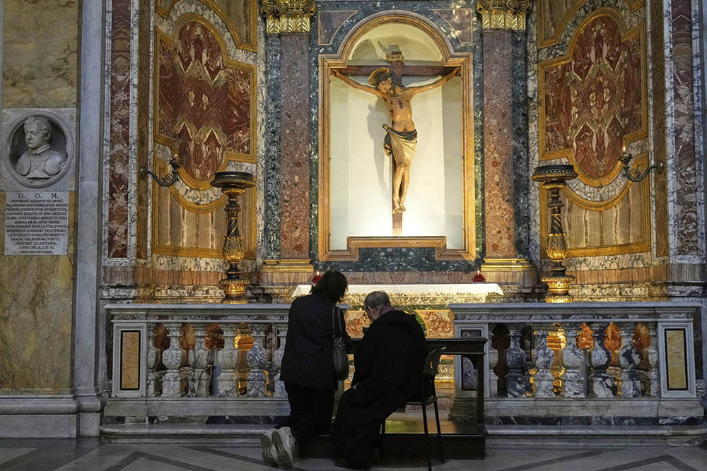 A priest takes a woman's confession inside the Basilica of St. Augustine where the Pilgrims' Madonna, of Caravaggio, is located in Rome on May 22, 2025. (AP Photo/Gregorio Borgia)